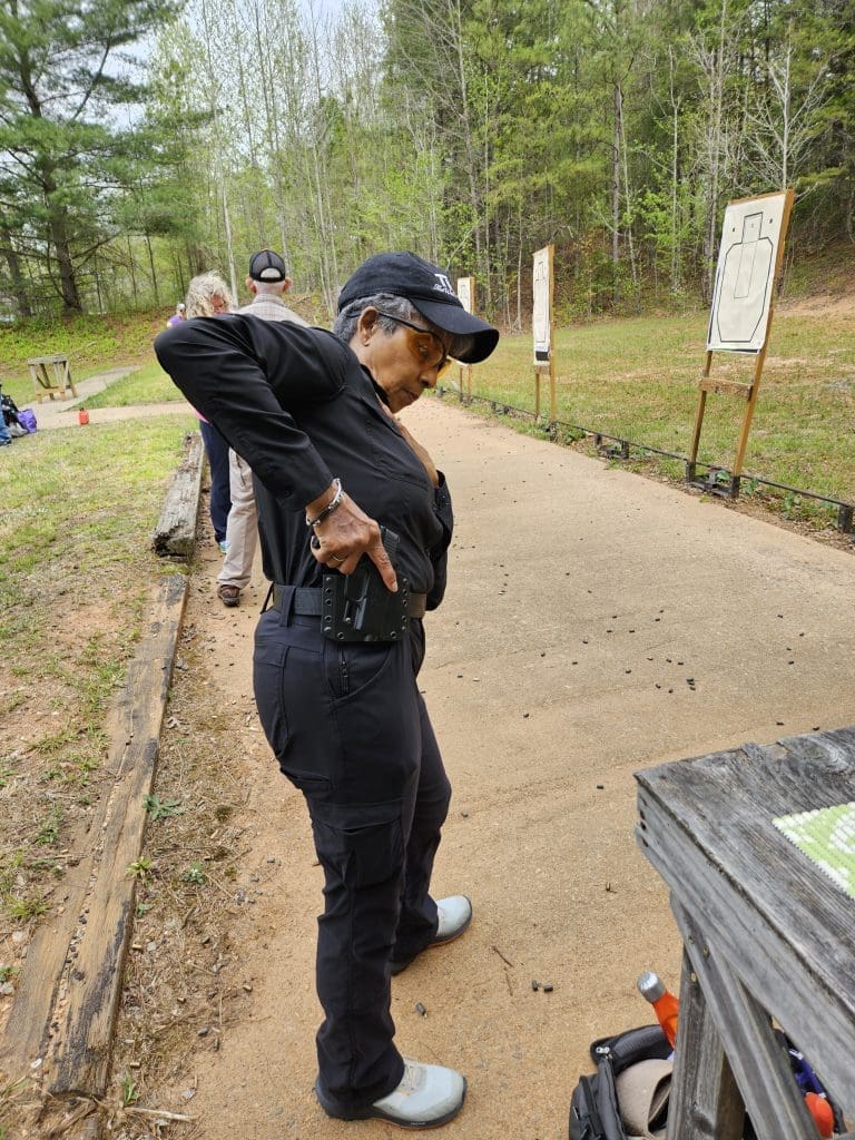 a woman at the range practicing drawing a gun from a holster with a short torso